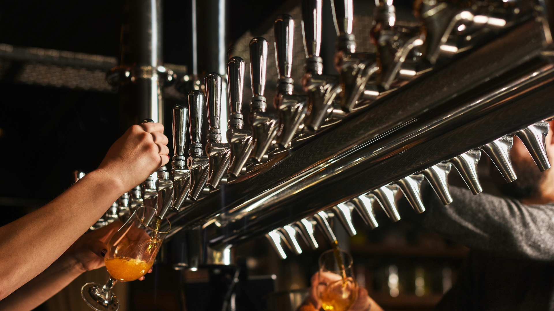 A hand pouring beer out of one of the taps at a brewery.