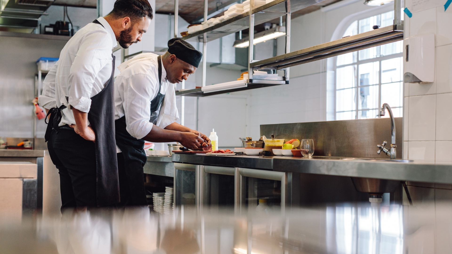 Commercial kitchen with two cooks making food.