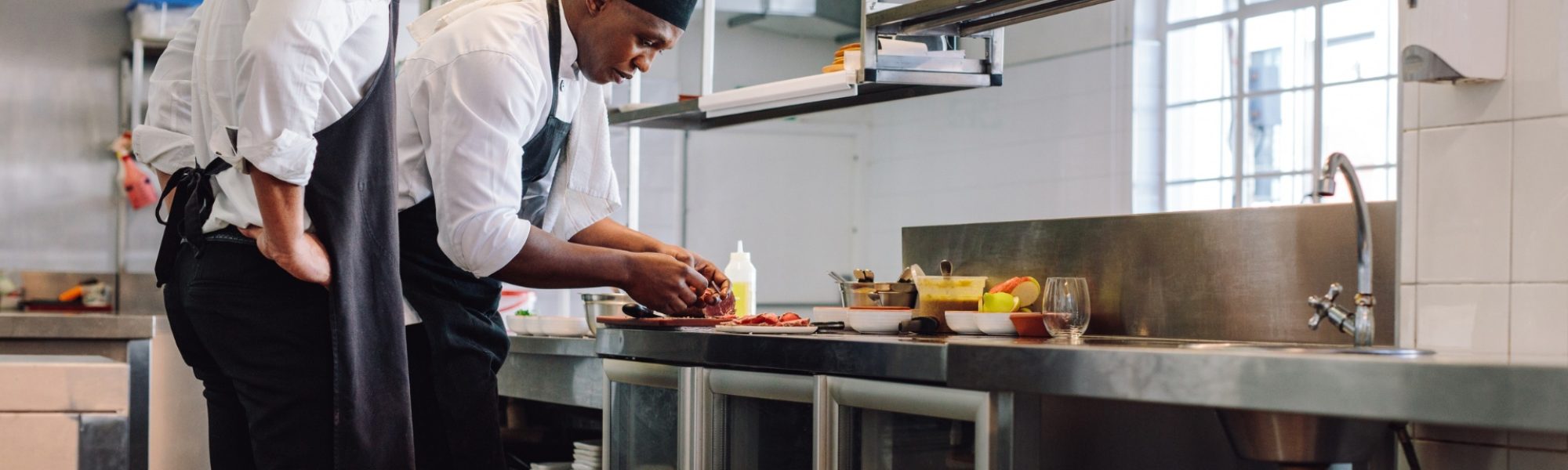 Commercial kitchen with two cooks making food.